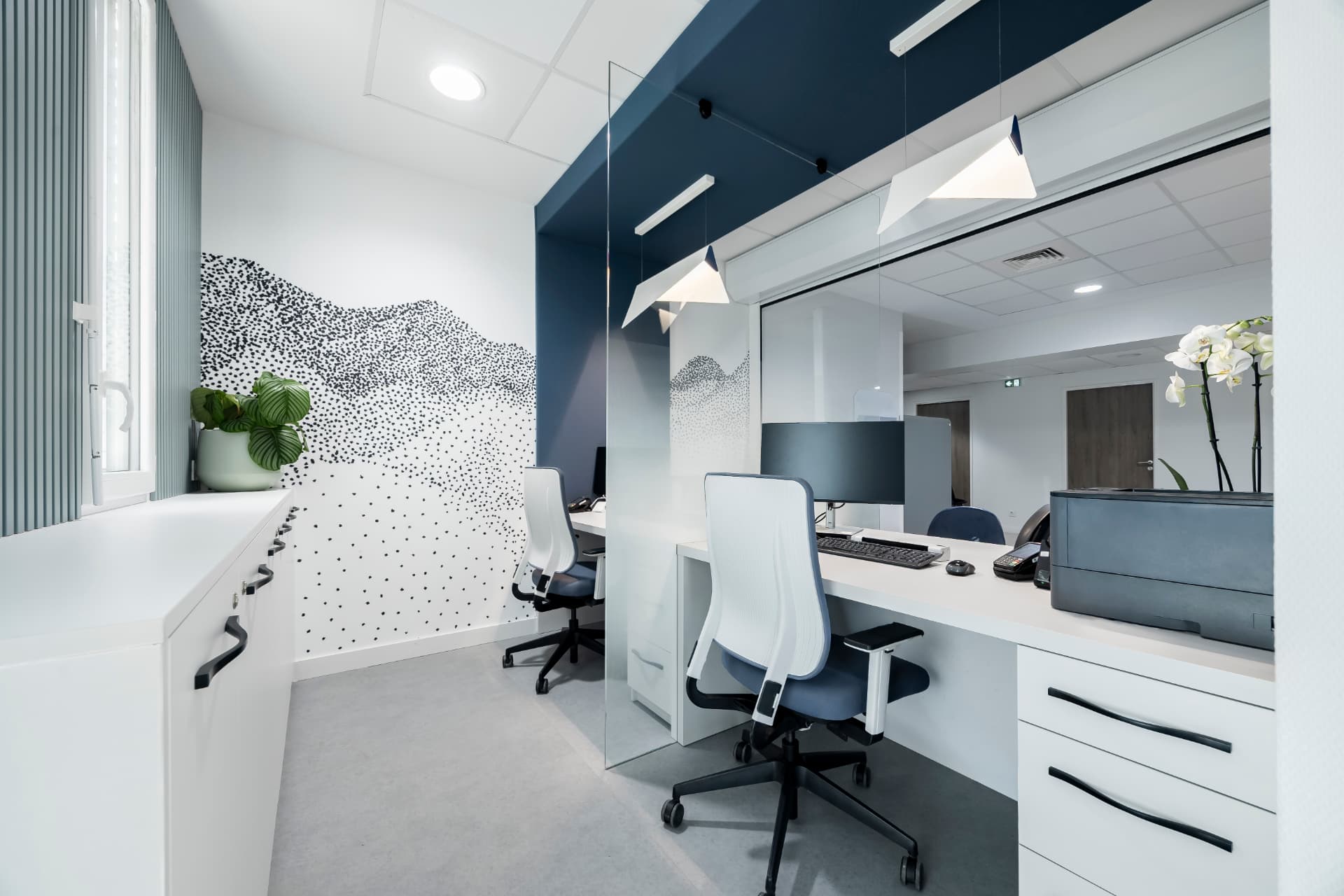 Bureau de secrétariat médical avec fresque murale, plantes et rangements blancs Bureau de secrétariat médical avec fresque murale, plantes et rangements blancs